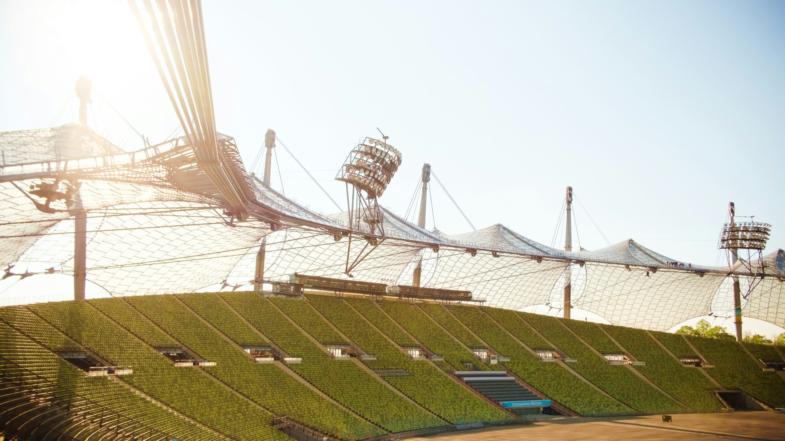 Panoramablick auf ein Stadion mit transparenter Dachkonstruktion bei Sonnenlicht.